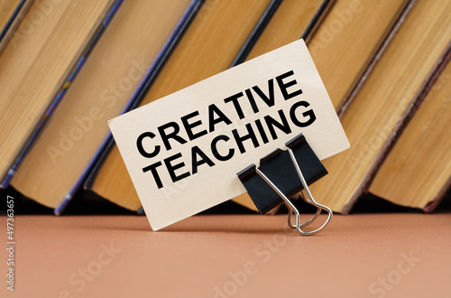 On the table against the background of books is a business card with the inscription - Creative Teaching photo