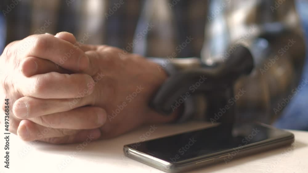 close-up of old man's hands and telephone on the table. An elderly man is waiting for a call, he is worried, he is depressed, he is going through. loneliness in old age. Lack of care. selective focus close-up of old man's hands and telephone on the table. An elderly man is waiting for a call, he is worried, he is depressed, he is going through. loneliness in old age. Lack of care. selective focus
