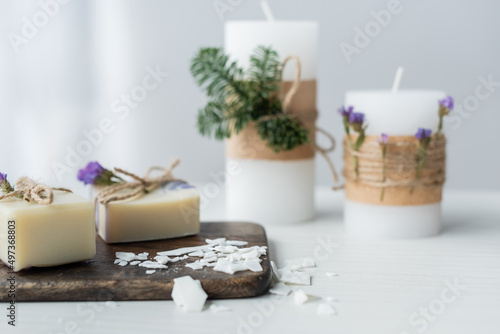 Craft soap on cutting board near blurred candles on table.
