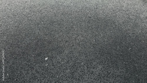snow falls on a black surface and melts metal black drops. High quality 4k footage