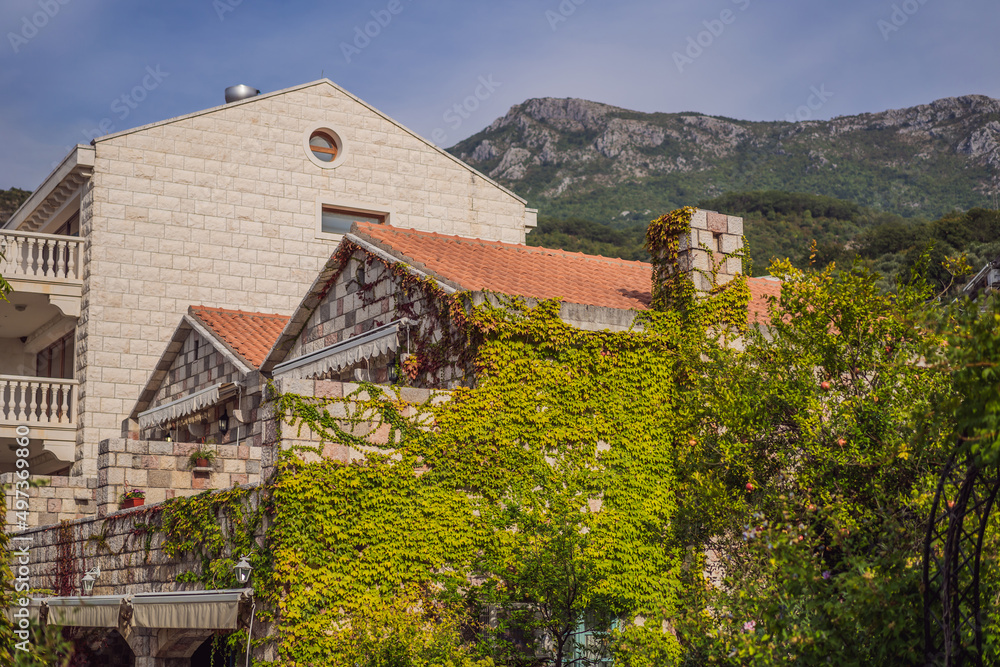 beautiful view of the mediterranean stone houses with a red tiled roofs and with balconies, the cozy yards, green trees, on a sunny summer day