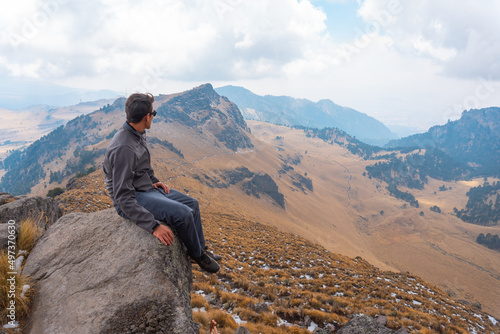 a man sitting on the ledge of a mountain