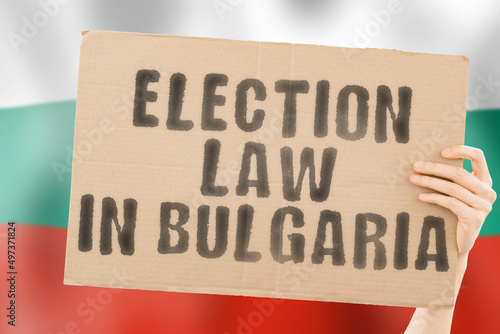 The phrase " Election law in Bulgaria " on a banner in men's hands with a blurred Bulgarian flag in the background. Constitution. Political. Senate. Sofia. Electorate. Majority © AndriiKoval