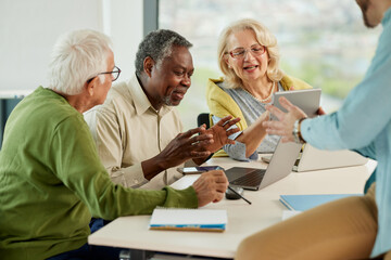 A group of multicultural senior students is discussing a programming project with an educator in the classroom.