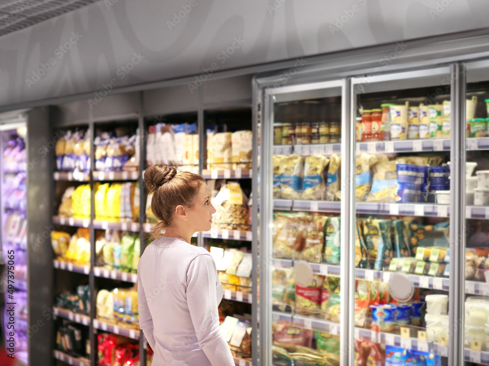 Woman choosing frozen food from a supermarket freezer.choosing a dairy products at supermarket.