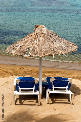 Empty beach with chairs  sunbeds  straw umbrellas  and blue sky. Mediterranean summer vacation destination  Heraklion  Crete  Greece.