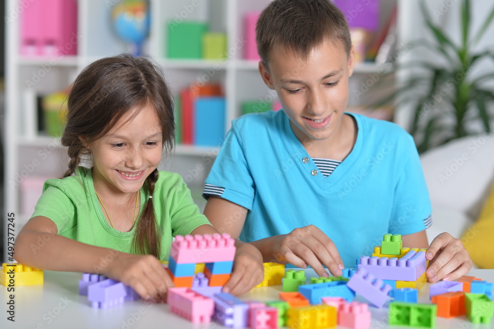 Brother and sister playing with colorful plastic blocks together Brother and sister playing with colorful plastic blocks together