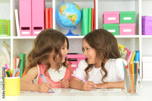 Two cute little girls drawing with pencils photo