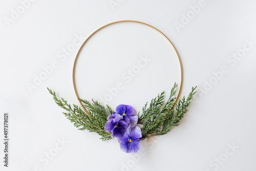 Gold frame with greenery and pansies on a white background