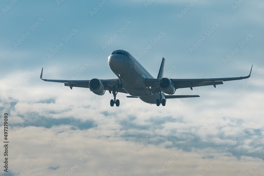 Modern twin jet engine descending from the clouds. Low flying passenger jet liner ready to land on an airport.