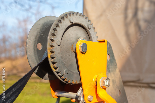 Hand winch mechanism close up. Iron gear of a traction winch with a tensioned belt. Loading and unloading of special equipment photo