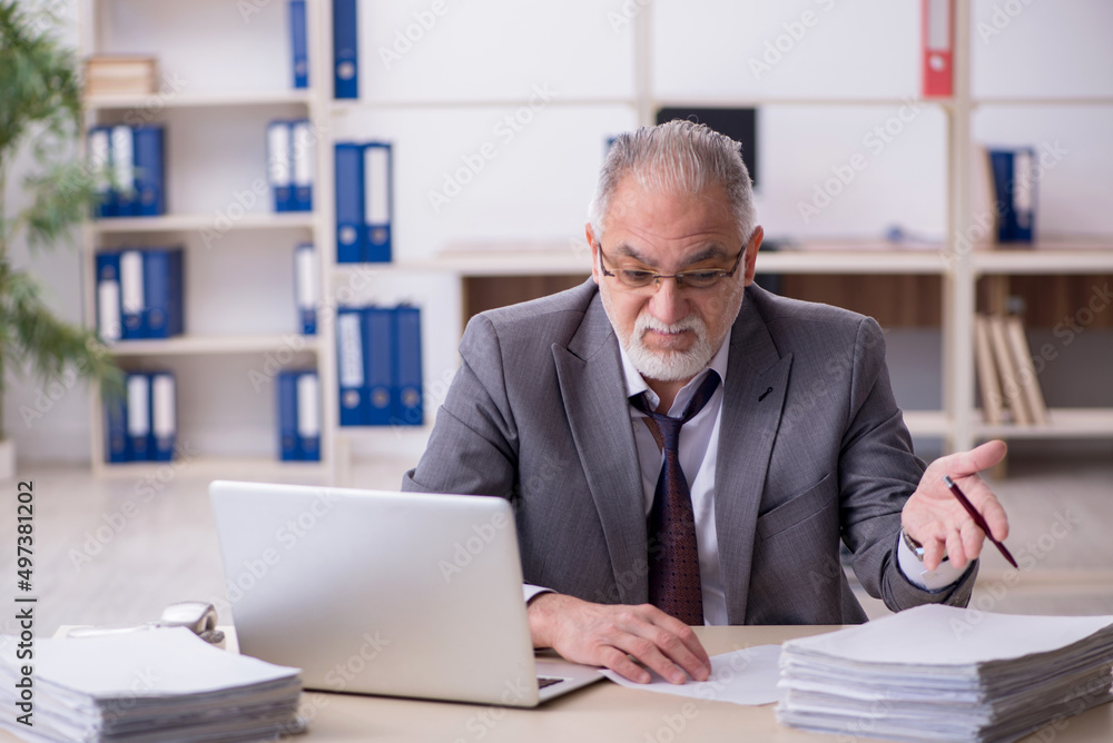 Old male employee unhappy with excessive work in the office Old male employee unhappy with excessive work in the office