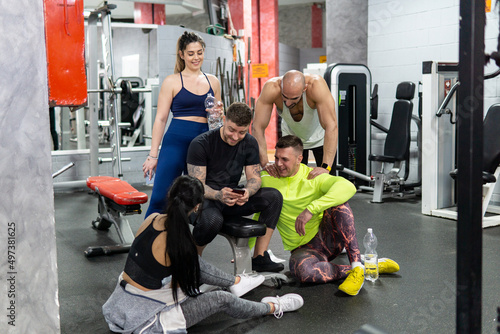 Group of friends resting and laughing in the gym. Healthy lifestyle, workout concept