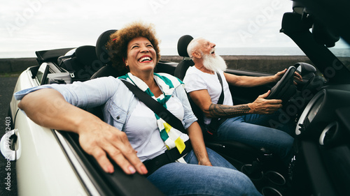 Happy senior couple having fun in convertible car during summer vacation - Focus on woman face