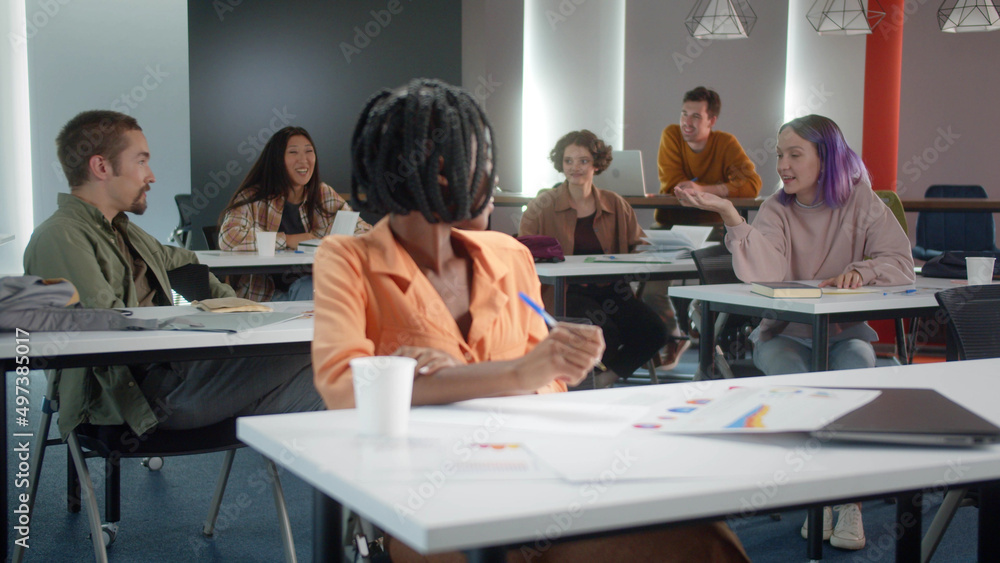 An attractive young african professor is preparing for the seminar, talking to her students and they are smiling together