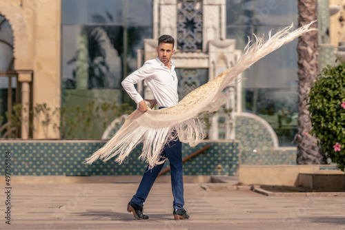 spanish flamenco dancer dressed in blue and white moving a manton around his body photo