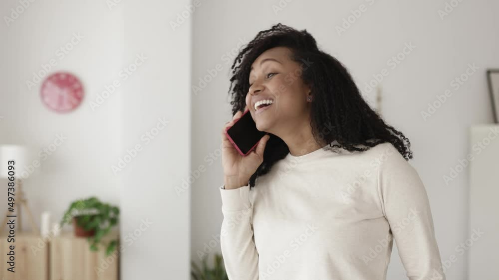 Excited young woman talking on smartphone device from home. Positive african american female having a conversation with friend on mobile phone. High quality 4k footage Excited young woman talking on smartphone device from home. Positive african american female having a conversation with friend on mobile phone. High quality 4k footage