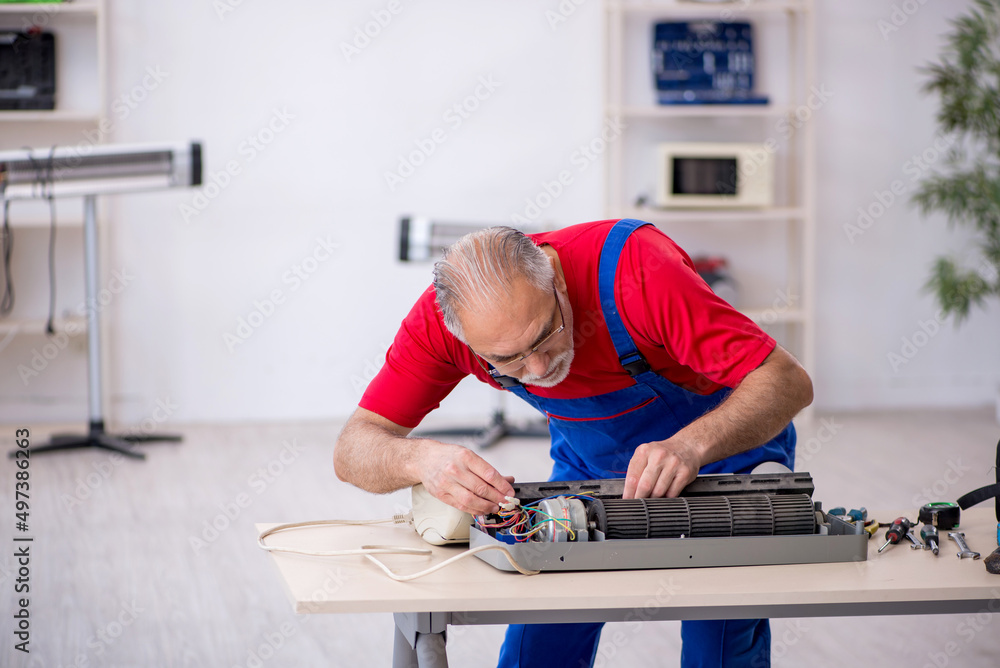 Old repairman repairing air-conditioner at workshop Old repairman repairing air-conditioner at workshop