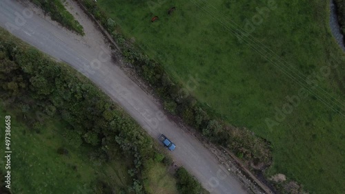 Cenital drone view of a car in the mountains with man walking