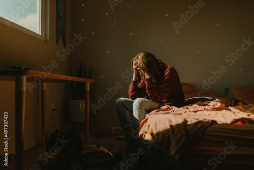 a woman with head in hands feeling anxiety and depression by window photo