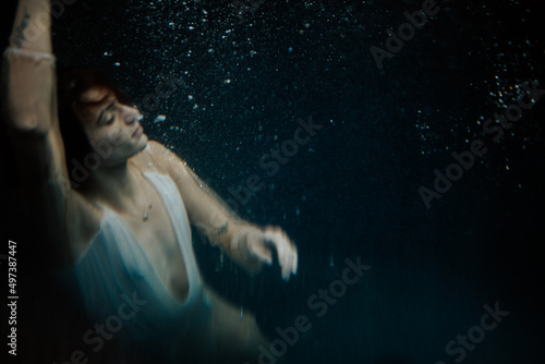 woman floating underwater with tattoos swimming in bubbles
