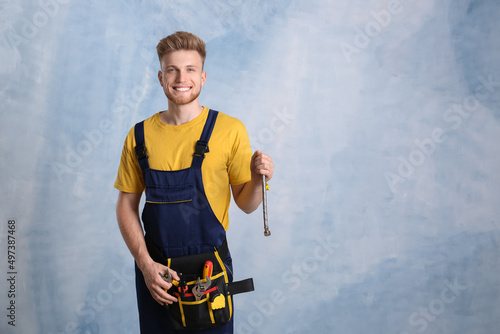 Handsome young plumber on color background