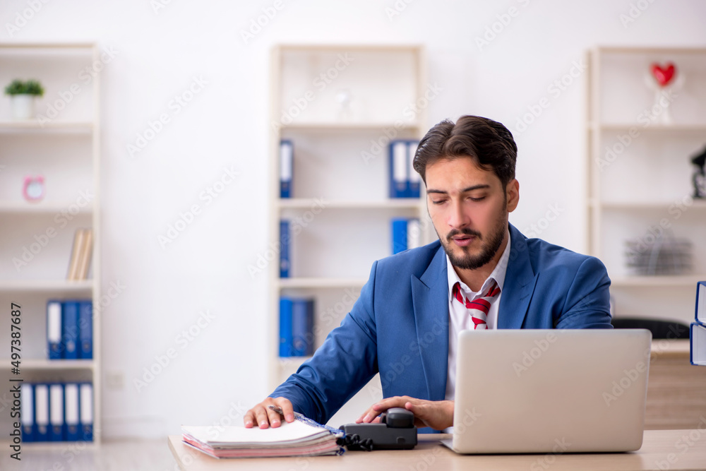 Young male employee and too much work in the office Young male employee and too much work in the office