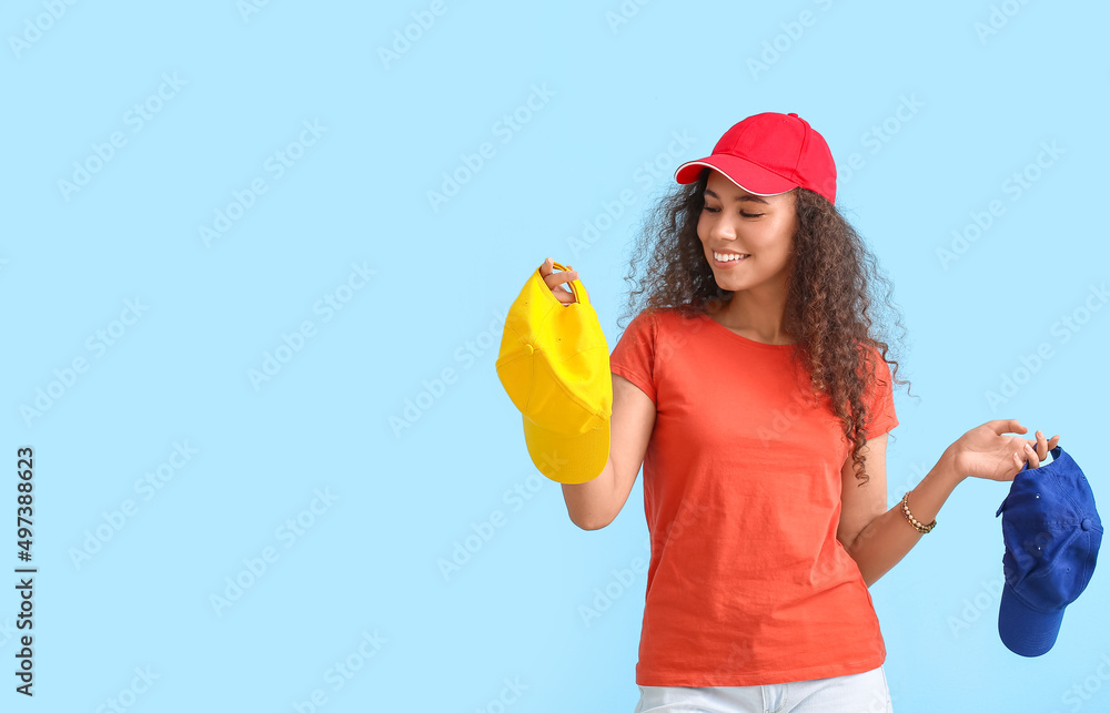 Beautiful African-American woman with stylish caps on color background Beautiful African-American woman with stylish caps on color background