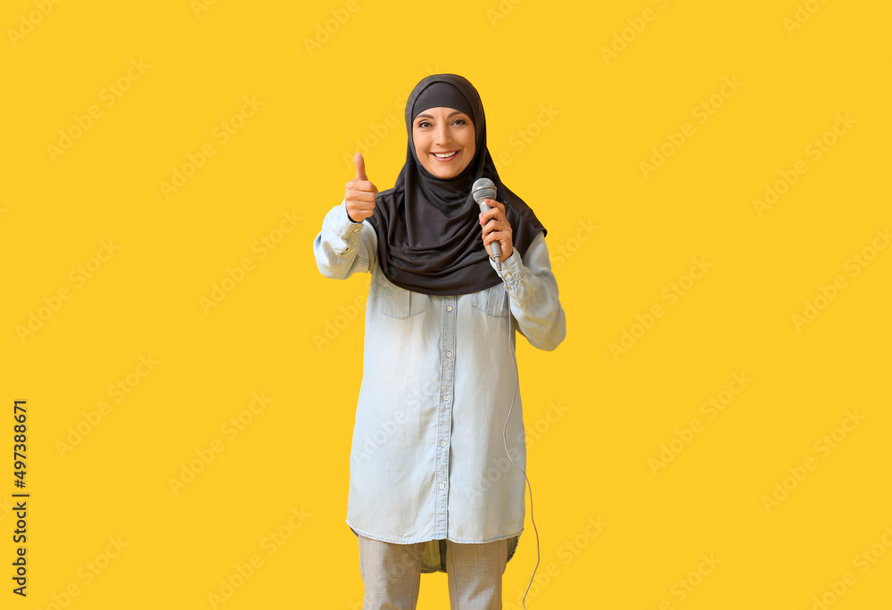Muslim music teacher with microphone showing thumb-up on color background Muslim music teacher with microphone showing thumb-up on color background