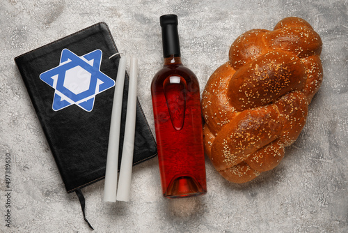 Torah with traditional challah bread, bottle of wine and candles on grunge background. Shabbat Shalom photo