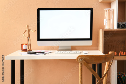 Workplace with modern computer, notebook, magnifier and decor near color wall © Pixel-Shot