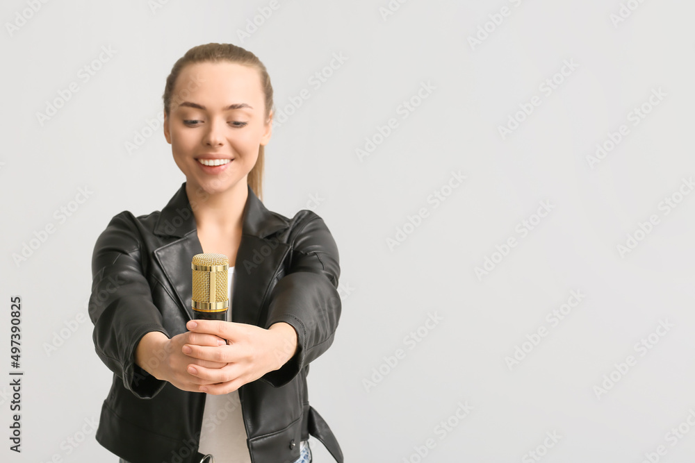 Young woman with professional microphone on light background, closeup Young woman with professional microphone on light background, closeup