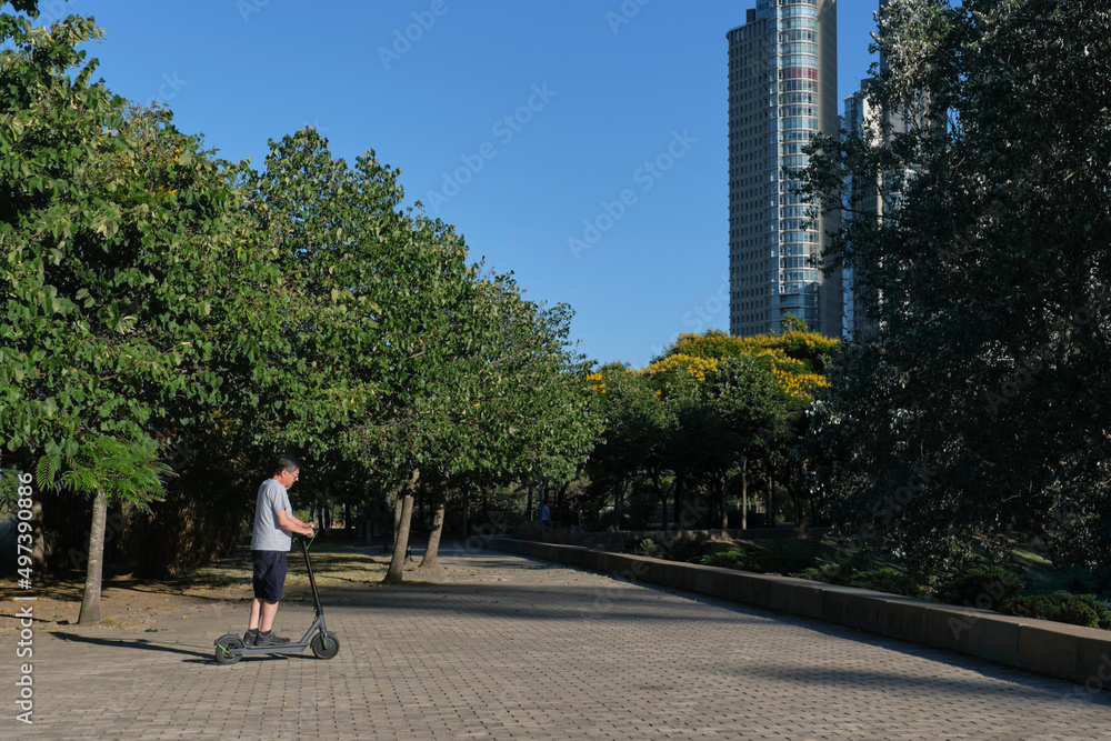 Hispanic senior man riding his electric kick scooter, modern transportation