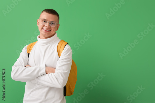 Male student in eyeglasses with backpack on green background © Pixel-Shot