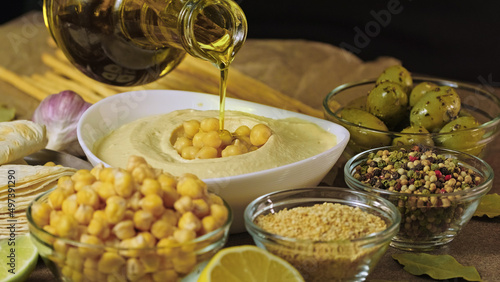 Chickpea hummus made from mashed chickpeas dip with tahini lemon garlic and olive oil close-up. Enjoying yummy hummus with pita, lavash, bread sticks, grissini. Kosher healthy vegan food. Lean dish