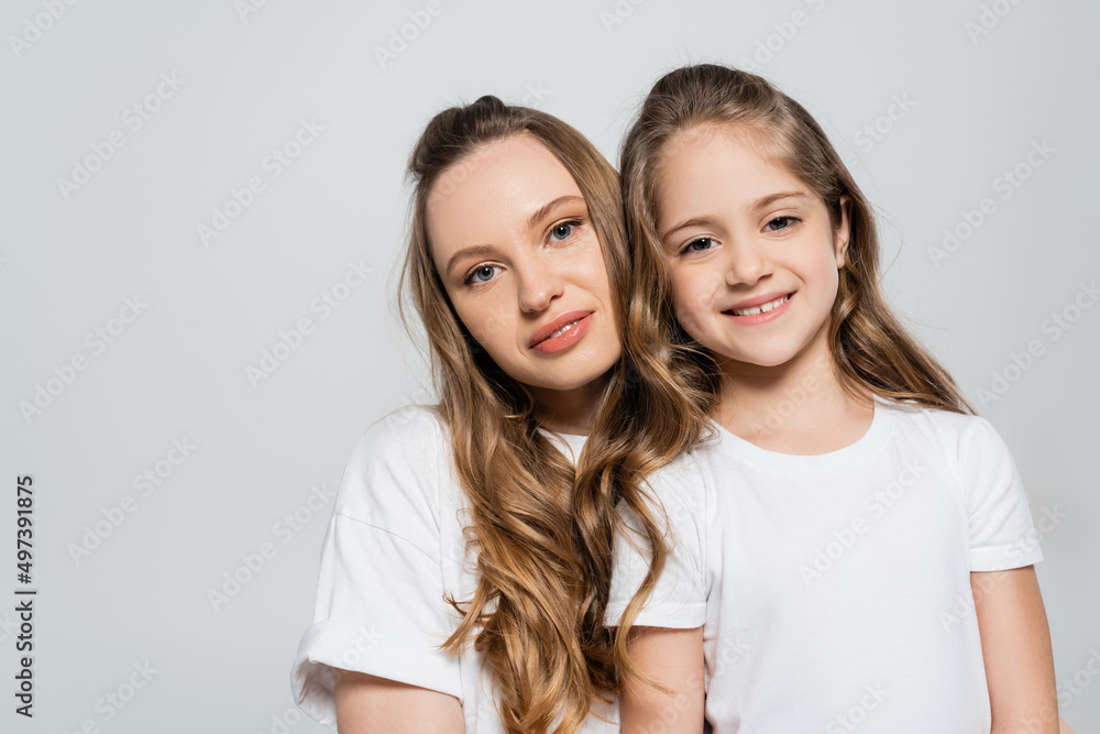 mother and daughter with long hair looking at camera isolated on grey. mother and daughter with long hair looking at camera isolated on grey.