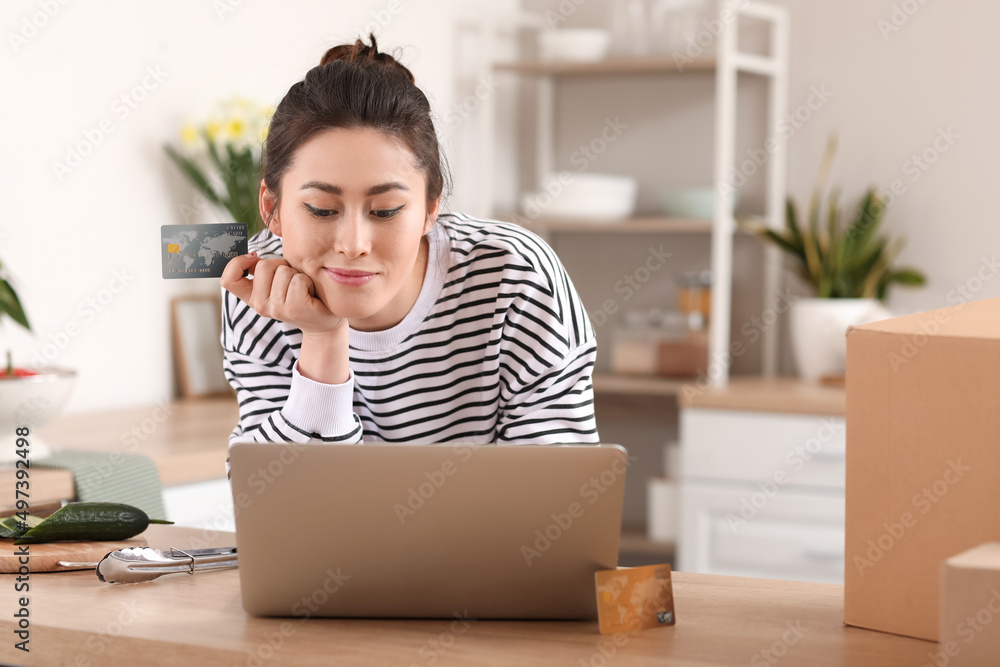 Young woman with laptop and credit card shopping online at home Young woman with laptop and credit card shopping online at home