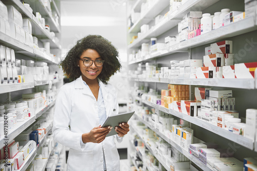 We have all the medication anybody would ever need. Portrait of a cheerful young female pharmacist standing with a digital tablet while looking at the camera in a pharmacy. photo