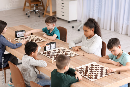 Tableau sur toile Little children playing chess during tournament in club