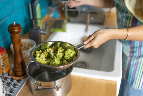 Woman washes broccoli in the sink