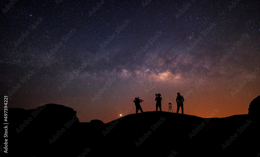 Teamwork and support. A group of people is standing together, beautiful, wide blue night sky with stars and Milky way galaxy. Astronomy, orientation, clear sky concept, and background.