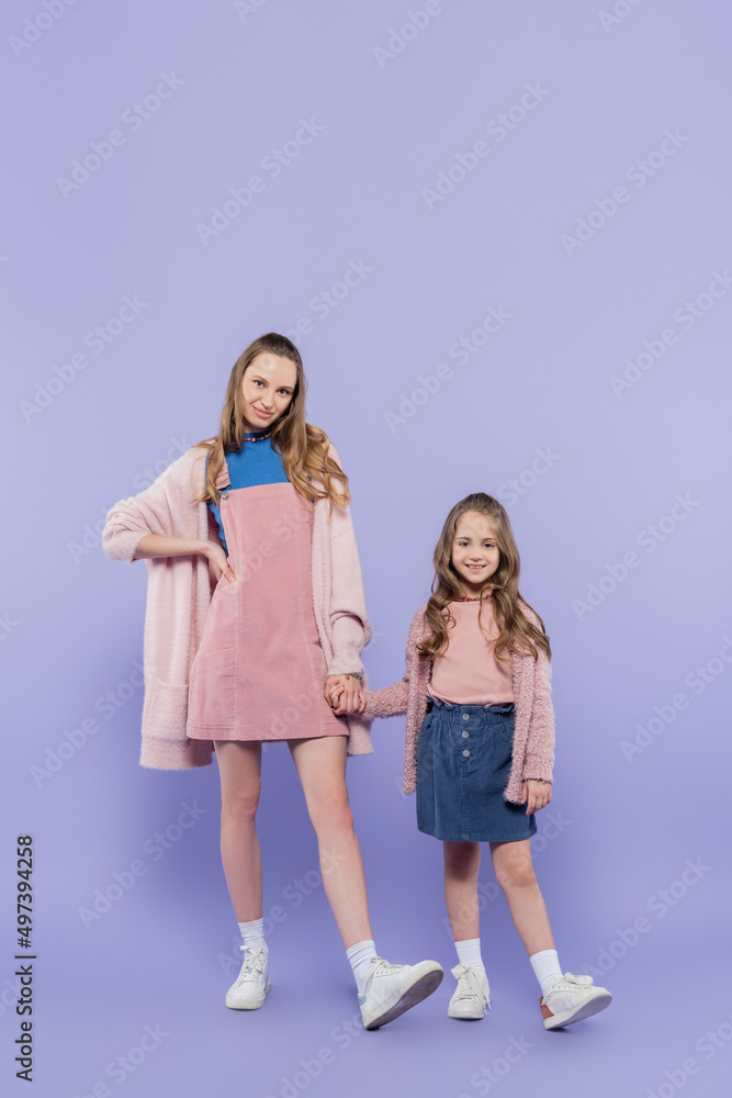 full length of happy kid and mother holding hands on purple. full length of happy kid and mother holding hands on purple.