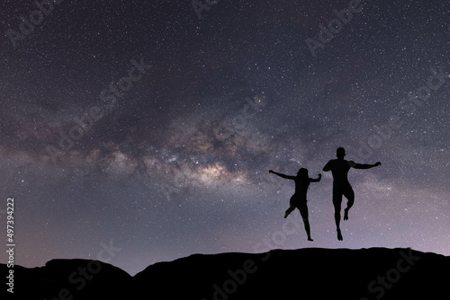 silhouette of happy people jumping over night sky with stars and Milky way galaxy. Astronomy, orientation, clear sky concept and background.