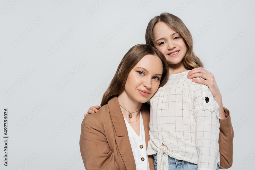 mother and daughter in stylish casual clothes embracing isolated on grey. mother and daughter in stylish casual clothes embracing isolated on grey.