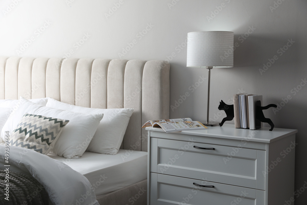 Stylish lamp, books and magazine on bedside table indoors. Bedroom interior elements Stylish lamp, books and magazine on bedside table indoors. Bedroom interior elements