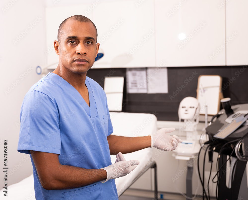 Obraz premium Professional experienced Hispanic male beautician welcoming in clinic of modern aesthetic medicine, telling about cosmetology treatments