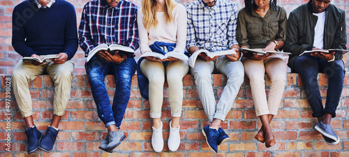 Studying on campus. Cropped shot of a group of unrecognizable university students studying while sitting outside on a facebrick wall. photo