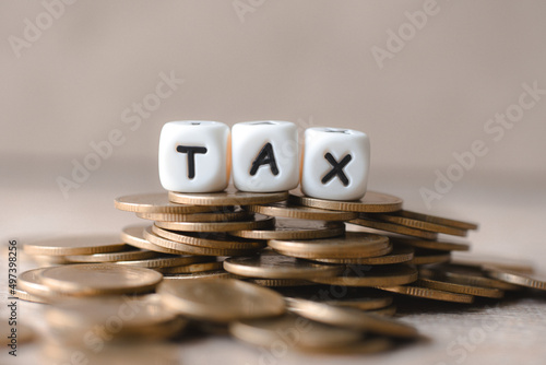 Block word tax on money on wooden background, TAX on stacked coins financial Tax concept.