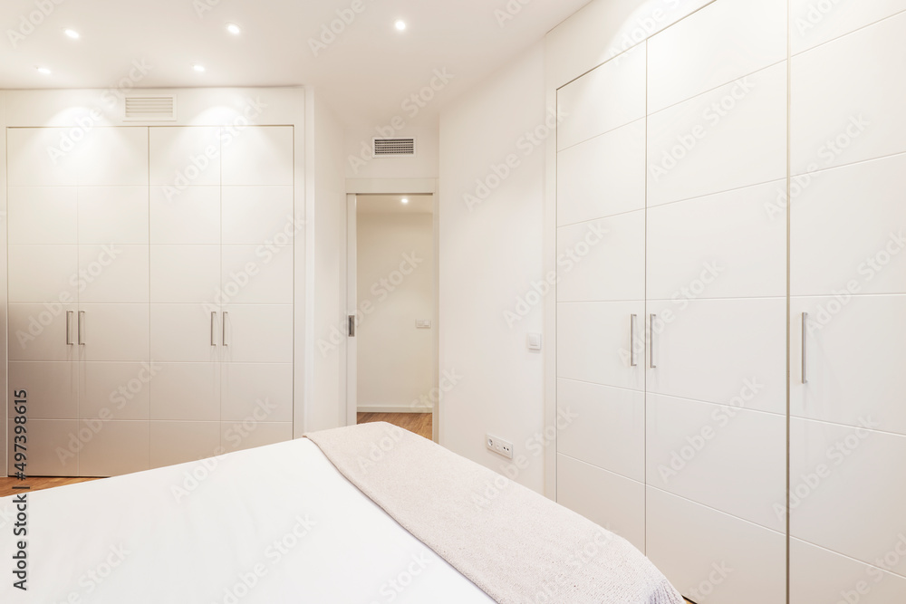 Double bedroom with gray wooden headboard, black bookcase, matching side tables and wardrobe with sliding doors in the background Double bedroom with gray wooden headboard, black bookcase, matching side tables and wardrobe with sliding doors in the background