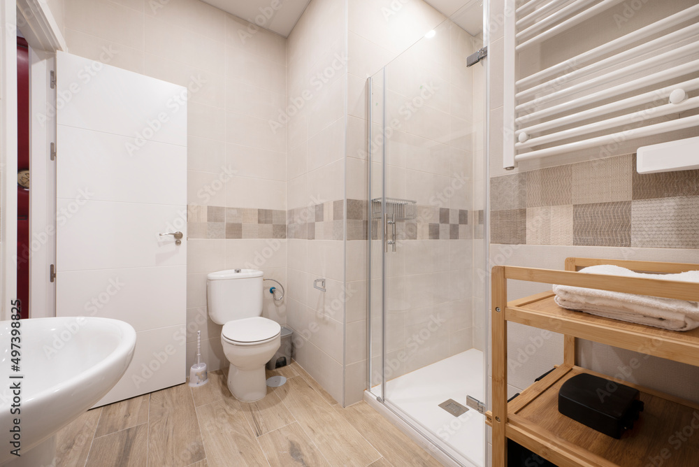 Bathroom with white porcelain sink, square shower stall with glass door, heated towel rail and bamboo wood shelf Bathroom with white porcelain sink, square shower stall with glass door, heated towel rail and bamboo wood shelf